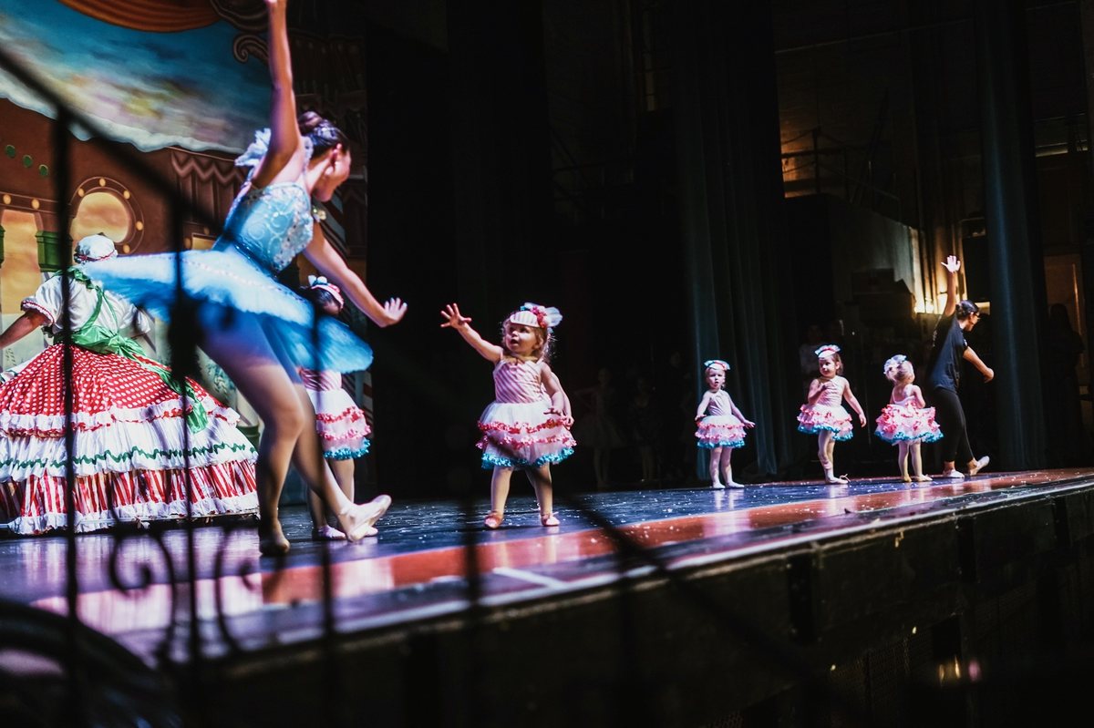 Group dance number on a lit stage with a painted backdrop