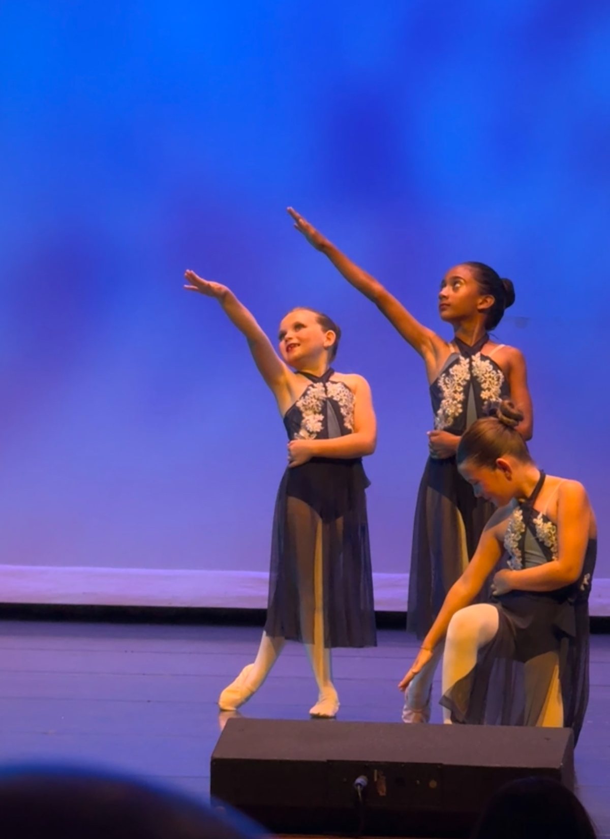 Three dancers in blue costumes on stage